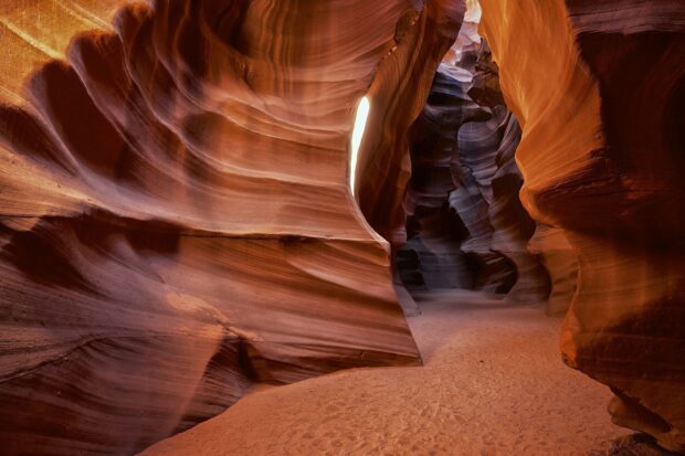 The Antelope Canyon rock formation displays vivid swirling patterns and light play in its narrow passage
