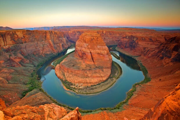 A breathtaking view of Antelope Canyon with a river winding through red rock formations at sunset