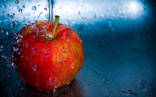 A fresh apple fruit being splashed with water in high definition quality