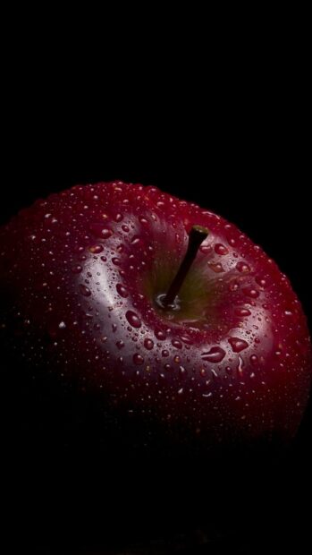 A close up view of a fresh apple fruit covered in water droplets