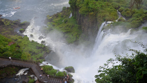 Beautiful Argentina natural waterfall surrounded by lush greenery and tourists on walkway