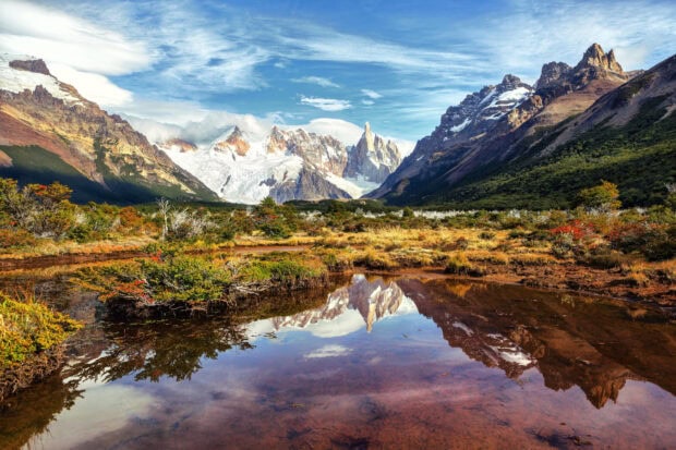 Snow covered mountains and colorful autumn plants in Argentina landscape reflection