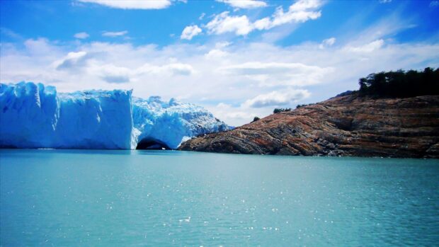 A glacier in Argentina with clear blue water under a bright sky