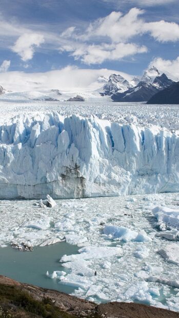 Massive glacier ice field in Argentina with towering ice formations and snowy mountains in the background