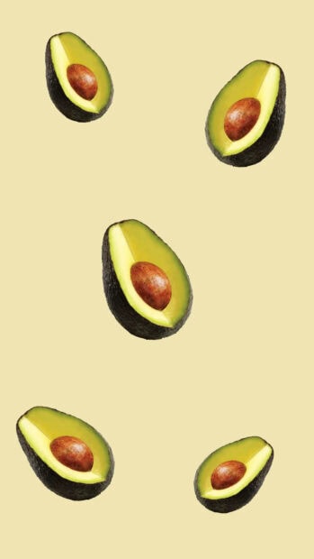 Halved avocado fruit pieces arranged on a light yellow surface
