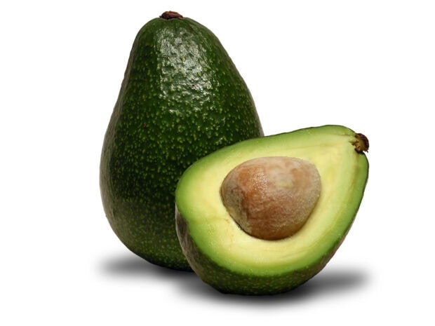 Fresh avocado with seed next to a whole avocado on white background