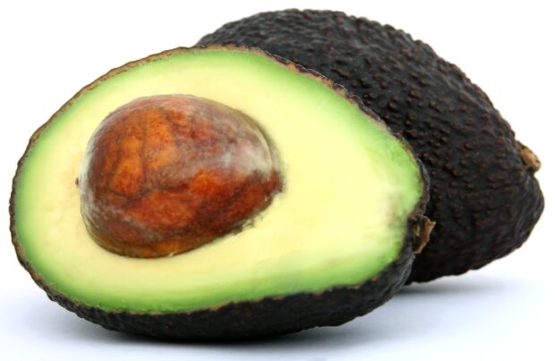A ripe avocado cut in half showing the seed and green flesh inside