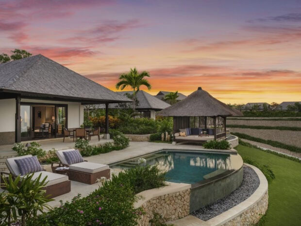 Luxury villa surrounded by tropical garden in Bali at sunset with a swimming pool and palm trees