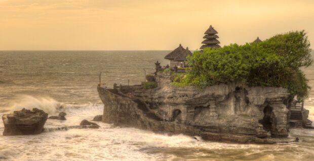 Tanah Lot temple on rocky cliff surrounded by ocean waves in Bali