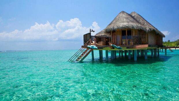 Overwater bungalow in Bali surrounded by crystal clear turquoise water and a blue sky