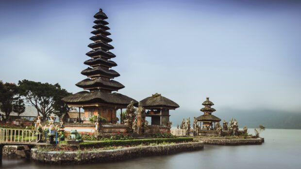 Traditional Balinese temple with tiered roofs by tranquil lake in Bali