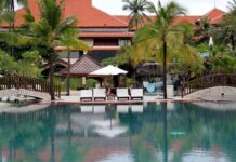 Tropical Bali resort with palm trees and poolside chairs at sunset