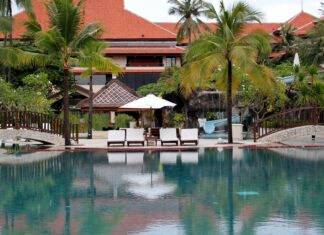 Tropical Bali resort with palm trees and poolside chairs at sunset