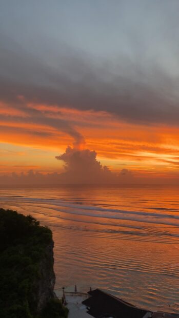 Bali sunset sky with ocean waves near cliff in Bali