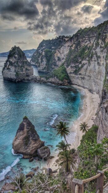 Stunning Bali cliffs and turquoise sea with sandy beach and palm trees at the coast