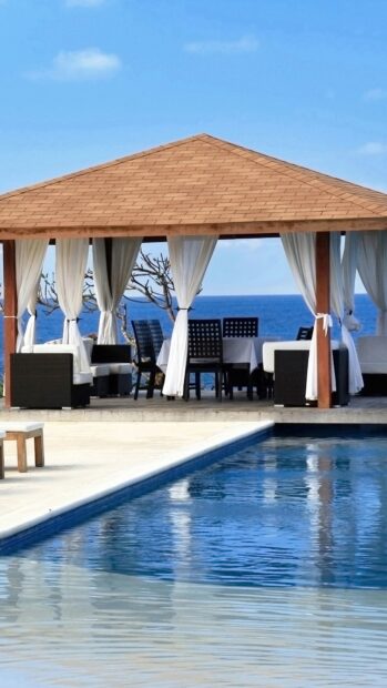 A Balinese gazebo with curtains beside a sparkling pool at a Bali resort