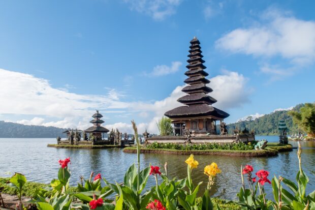 Traditional Balinese architecture on a serene lake with colorful flowers in Bali