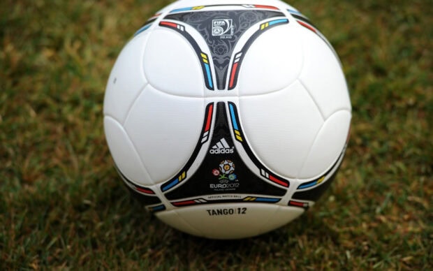 Close up of a soccer ball on grass with Adidas logo and colorful design