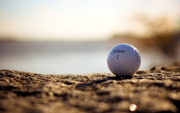 A golf ball resting on rough terrain during sunset with a blurred background