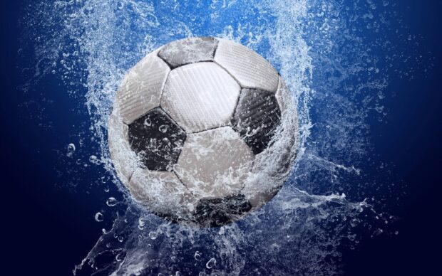A soccer ball splashing through water droplets on a blue background