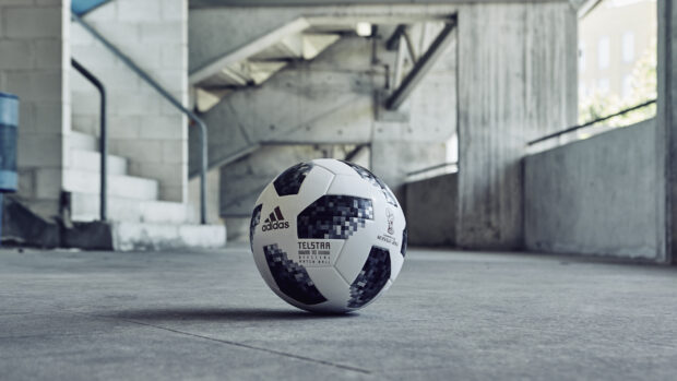 A Telstar ball with black and white patterns resting on a concrete floor in a stadium corridor