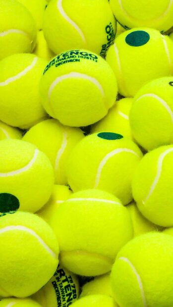 A close up of multiple tennis balls stacked together showing detailed texture and color