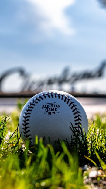 A high quality baseball sitting on grass with Cleveland text blurred in the background