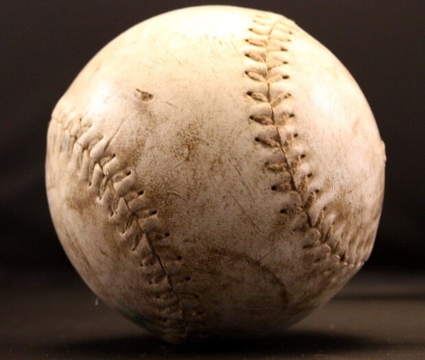 A close up of a worn baseball showing detailed stitching and texture