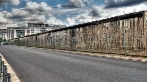 Graffiti covered section of the Berlin Wall along an empty street in the city