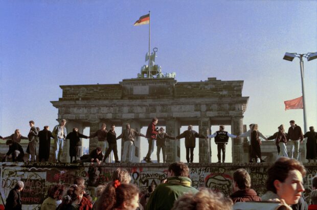 People holding hands on the Berlin Wall in front of the Brandenburg Gate