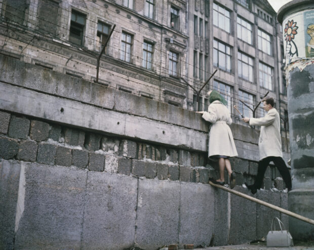 A couple climbing the Berlin Wall showing the historic border crossing in Berlin Wall