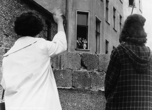 People waving across the Berlin Wall during the historic division event