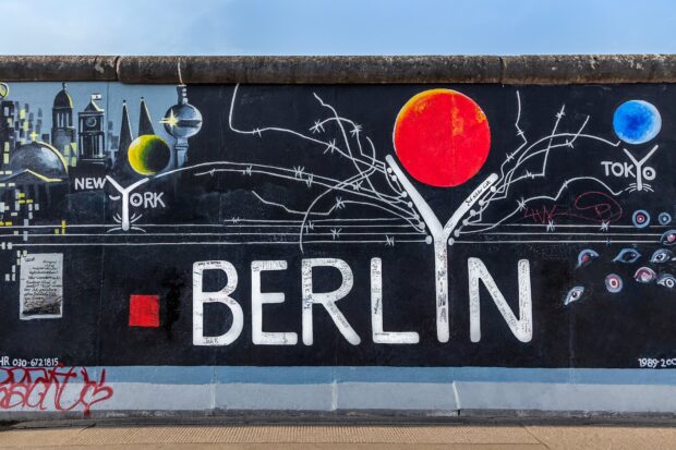 The Berlin Wall graffiti artwork featuring the word Berlin and city references on a high quality Berlin Wall