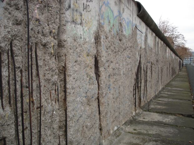 Close up view of the Berlin Wall showing concrete texture and rusted rebar exposed along the pathway