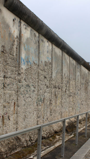 The weathered Berlin Wall showcasing historic graffiti and concrete textures in a vertical view