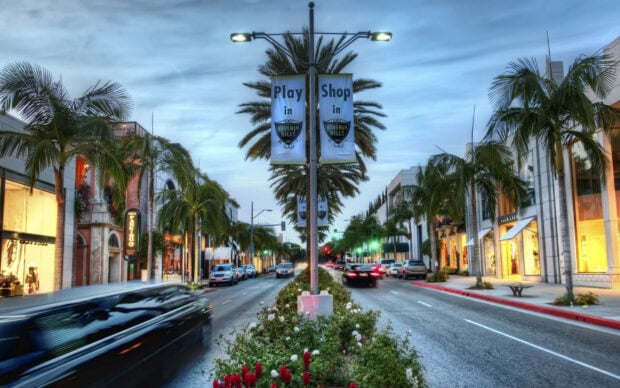 The vibrant street of Beverly Hills with palm trees and luxury shops in the evening light