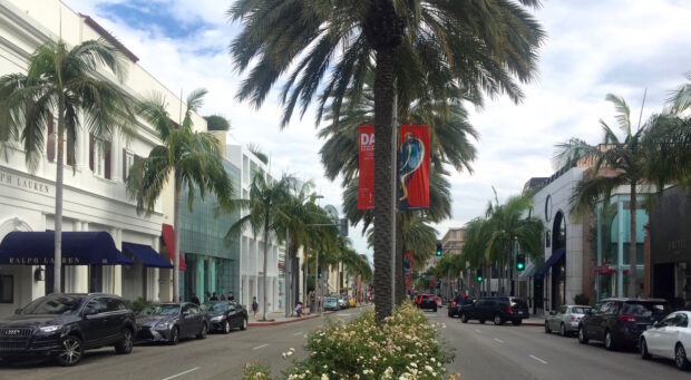 A busy Beverly Hills street lined with palm trees and luxury shops in clear daylight