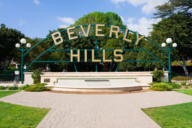 The famous Beverly Hills sign surrounded by greenery and clear blue sky