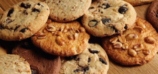 A close up view of assorted biscuit variety with chocolate chips and peanuts on wooden surface