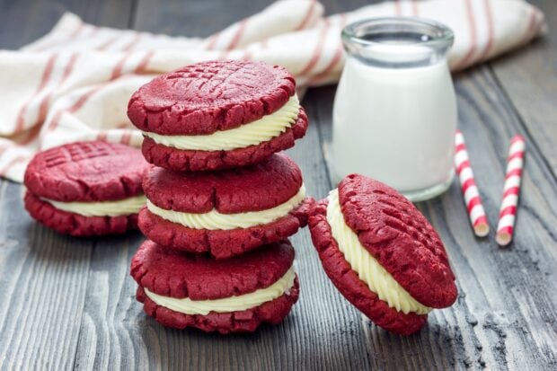A stack of red velvet biscuit with cream filling on a wooden table