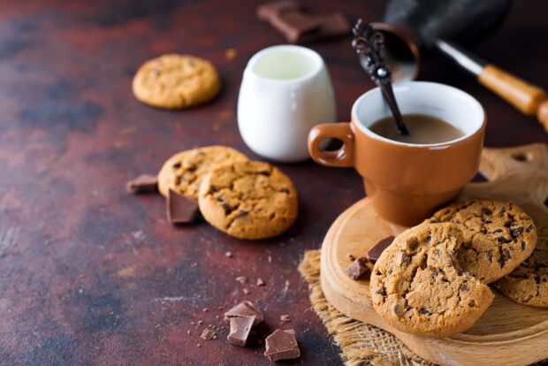Chocolate chip biscuit with coffee and milk on wooden board