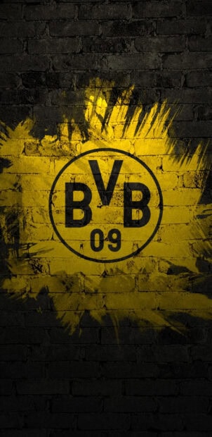 Borussia Dortmund logo graffiti on a black brick wall with yellow paint splash