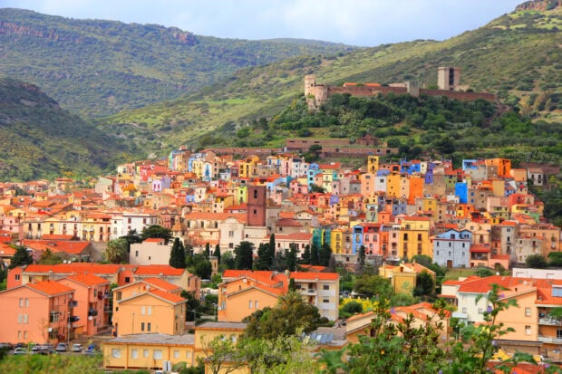 Colorful houses and historic castle in Bosa Italy surrounded by green hills