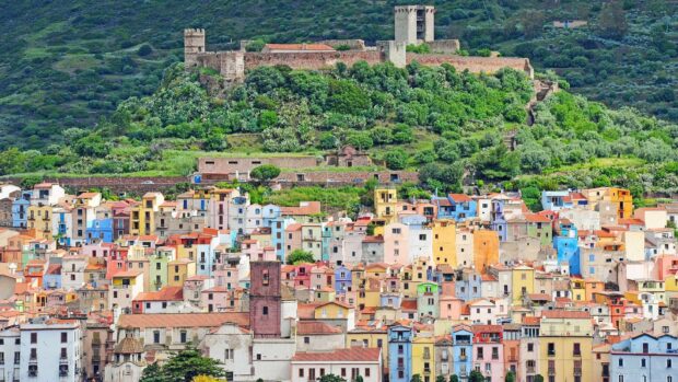 Colorful houses in Bosa Italy with ancient castle on green hill