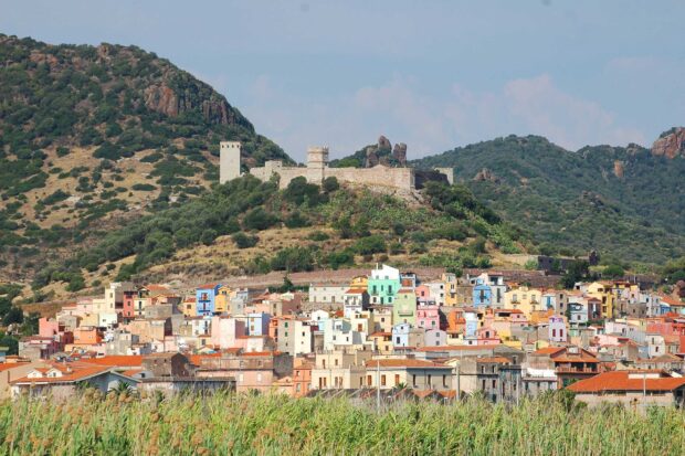 Colorful houses on the hillside in Bosa Italy surrounded by green vegetation