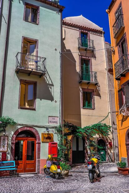 Colorful street view of Bosa Italy with vintage scooters and classic buildings