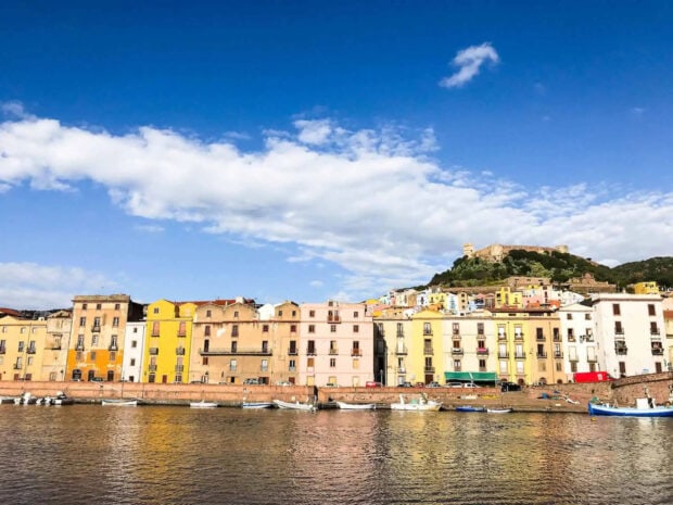 Colorful buildings along the waterfront in Bosa Italy under a bright blue sky