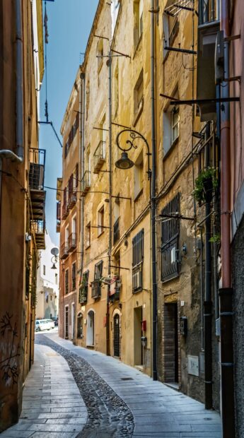 Narrow cobblestone street in old Bosa Italy with historic buildings and balcony details