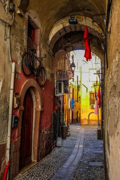 Narrow cobblestone street in Bosa Italy with hanging clothes and old buildings