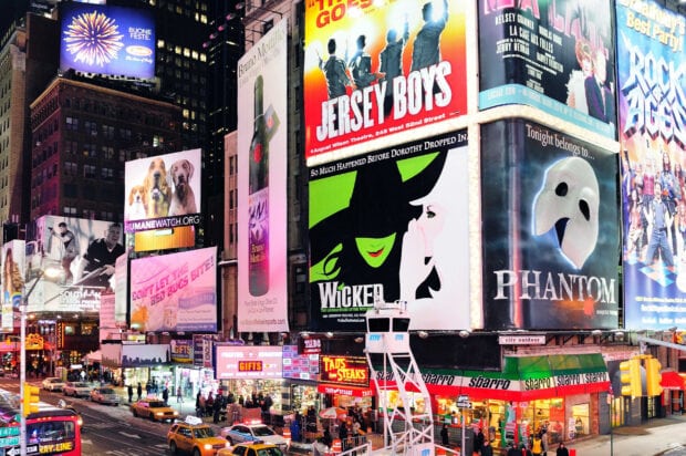 Bright Broadway scene featuring Wicked and Phantom billboards at night in New York City